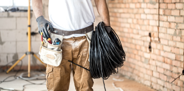 A man with tools and holding cables